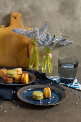 Macaroons and coffee. Dark blue plate, gray background. 
