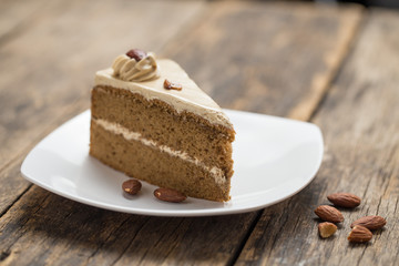 chocolate cake slice with almonds on plate on wooden table