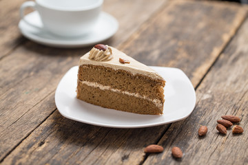 chocolate cake slice with almonds on plate on wooden table