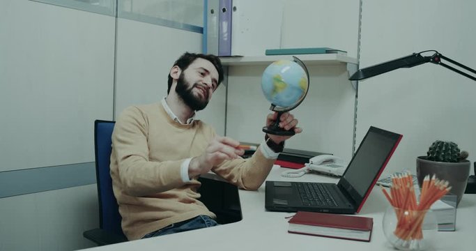 Travel agency , charismatic agent sitting on his desk and playing with a geographic clipart having smiling and happy face
