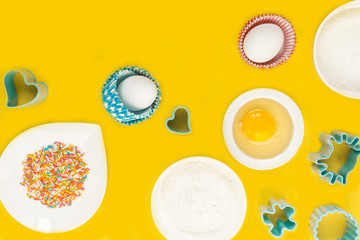 concept of the Easter bakery, various products for home baking, sugar, eggs and flour, coconut munt, top view, empty space for text on a yellow background in the style of pop art mocap layout