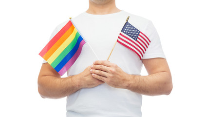 lgbt, same-sex relationships and homosexual concept - close up of man wearing gay pride rainbow awareness wristband and holding american flag