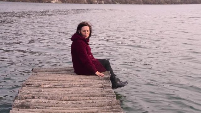Beautiful woman sitting on a old bridge and looking at her