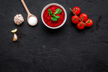 Ingredients for tomato sauce. Cherry tomatoes, garlic, green basil, black pepper, salt in spoon on black background top view space for text