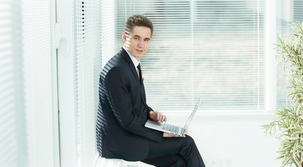 young employee working on a laptop sitting in the corridor of the office