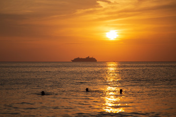 Naklejka na ściany i meble Cruise liner on the horizon against the setting sun