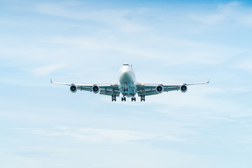 Airplane aircraft flying, landing in the good weather at blue cloudy sky