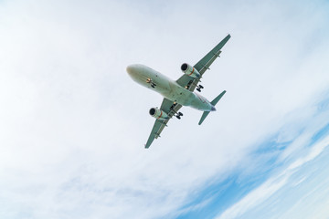 Airplane aircraft flying, landing in the good weather at blue cloudy sky