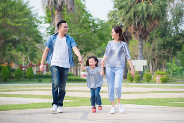 Happy Asian family walking together in park