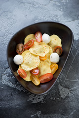 Black bowl with italian ravioli on a weathered grey concrete background, vertical shot, elevated view