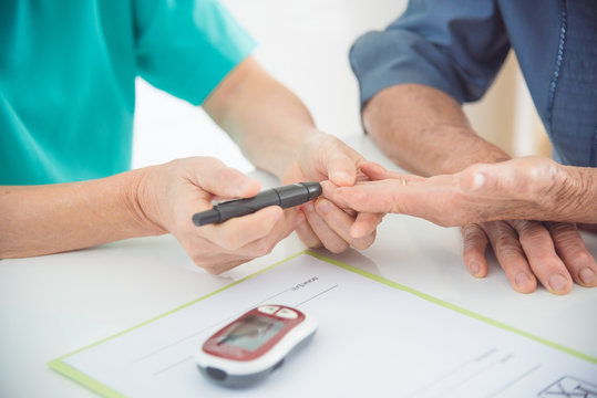 Close up of nurse hands using lancet to checking patient blood sugar level by Glucose meter ,diabetes concept