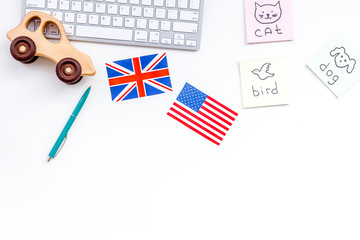 Teach english to a child. Funny english. British and american flags, computer keyboard, stickers with vocabulary, toy on white background top view copy space