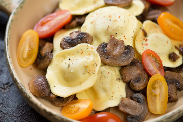 Close-up of ravioli with roasted mushrooms and cherry tomatoes, studio shot