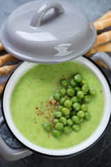 Closeup of cream-soup with green peas served in a grey pan, high angle view, vertical shot