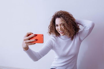 Close-up portrait of a young cheerful redhead woman in a Vadalaz making herself on a smartphone, on...