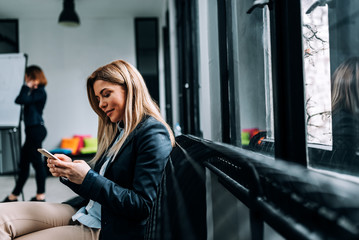 Side view of blonde business woman using smartphone.