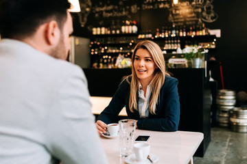 Young businesswoman talking to a male friend at the cafe.