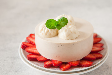 Light cheesecake with strawberry filling decorated with fresh berries and min, healthy organic summer dessert pie.