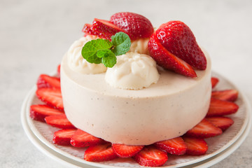 Light cheesecake with strawberry filling decorated with fresh berries and min, healthy organic summer dessert pie.