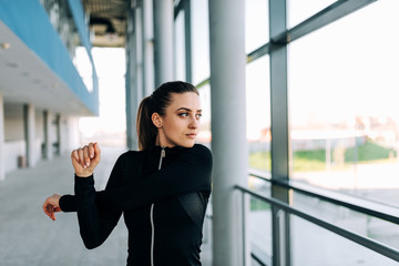 Fototapeta premium Attractive girl in black sportwear stretching arms. Close-up.