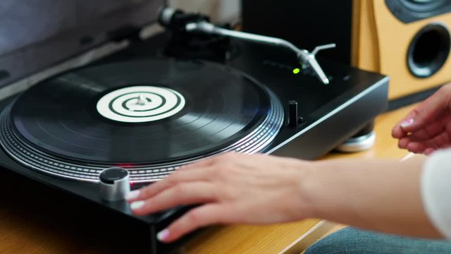 woman turns off the turntable takes the LP and finishes listening to music