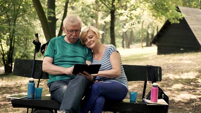 Senior couple reading something on ebook in the forest
