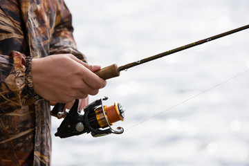 A fisherman catches a fish. Hands of a fisherman with a spinning rod in hand closeup