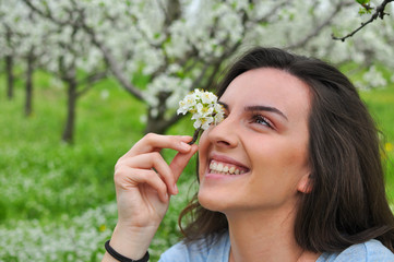 Portrait of beautiful woman with little blooming branch. Happy girl in spring time in nature
