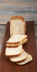 Many mixed breads and rolls of baked bread on wooden table background.