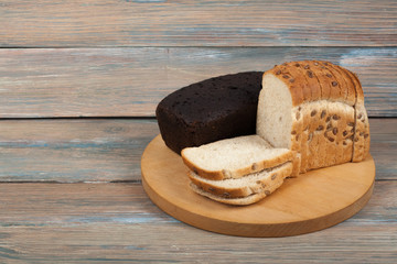 Many mixed breads and rolls of baked bread on wooden table background.