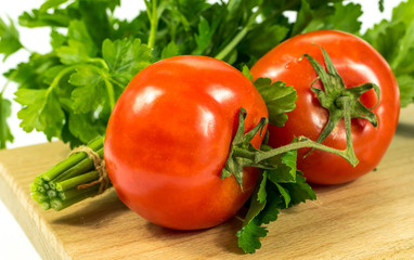 Ripe juicy tomatoes and parsley on a cutting board