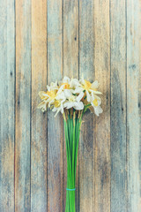 bouquet of daffodils flowers on wooden retro grunge background closeup