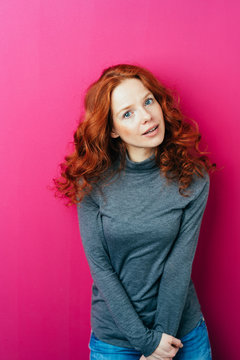 Young red-haired woman against pink background