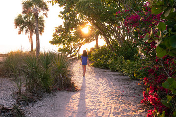Girl walking on sandy beach trail at sunset
