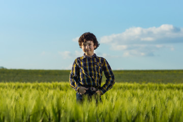 Naklejka na ściany i meble A boy in jeans and a shirt is standing in the field.