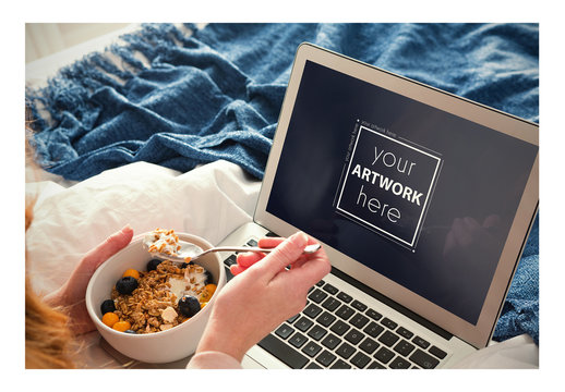 Woman Using Laptop in Bed While Eating Breakfast Mockup