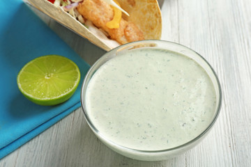 Tasty creamy lime sauce for fish taco in bowl on table