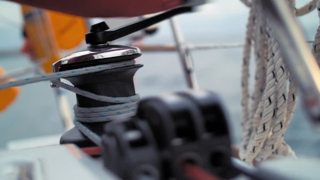 Preparing ropes for changing sailing boat direction. Getting ready for making a turn of vessel. Yachting. Sailing winch, ropes and other details of yacht. Life jackets in the background. Sea journey
