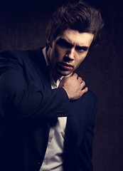 Fototapeta premium Sexy serious business man posing in blue suit and white style shirt with vamp look on dark shadow background. Fashion toned style vogue portrait