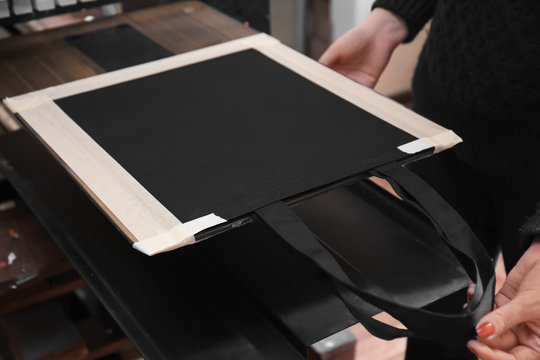 Young woman printing on bag at workshop