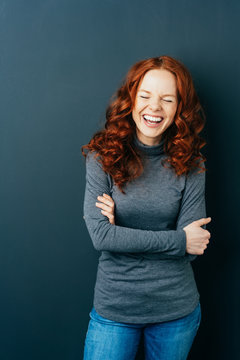 Young laughing red-haired woman on dark background