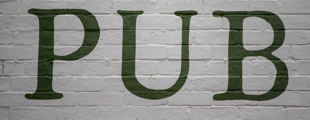 Pub sign in green on brick