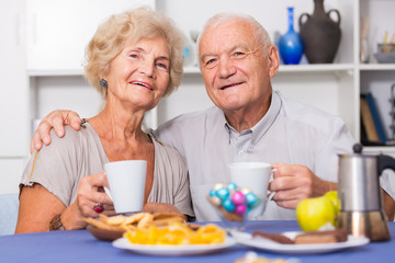 Happy senior couple enjoying conversation over cup of coffee