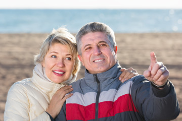 smiling husband and wife show each other hands interesting things outdoors