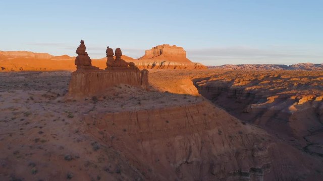 Aerial view flying towards the Sisters hoodoo in Goblin Valley at sunrise towards Wild Horse butte.
