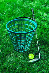 A set of golf equipment, stick, bin and a ball on a green grass background,  luxury sport play game lifestyle concept.