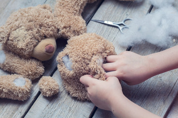 A girl sews a bear toy. Handicraft with children. Child fills the toy with a sintepon.