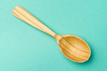 Wooden spoon on a turquoise background.Spoon with textured tree. Trend Colors . Copy space