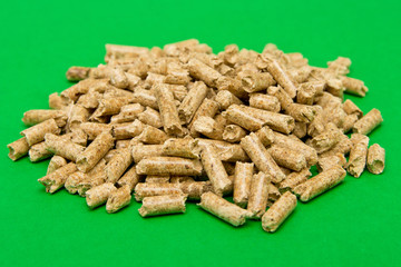 Wood pellets on a green background , copy space. Biofuels