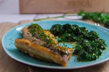 Fried fish with herbs and spinach puree on a plate